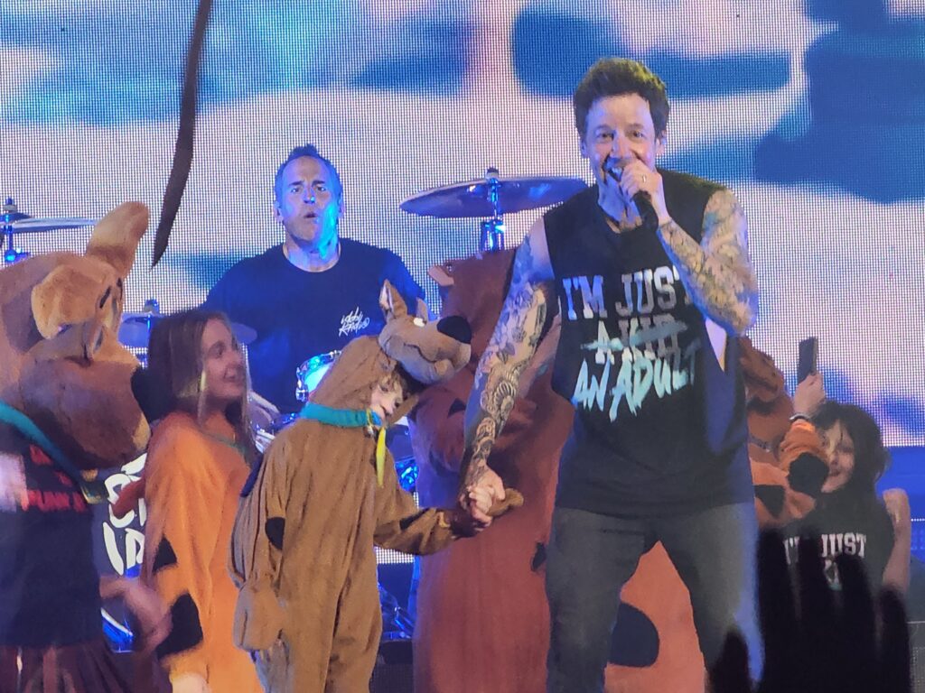 Pierre Bouvier of Simple Plan holds hands with a fan dressed as Scooby Doo.